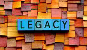 The image displays the word LEGACY in colour F7AO72 block letters positioned in the centre of colour B5E2FA background-3
